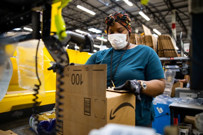 Un employé d'un entrepôt Amazon qui emballe une boîte.