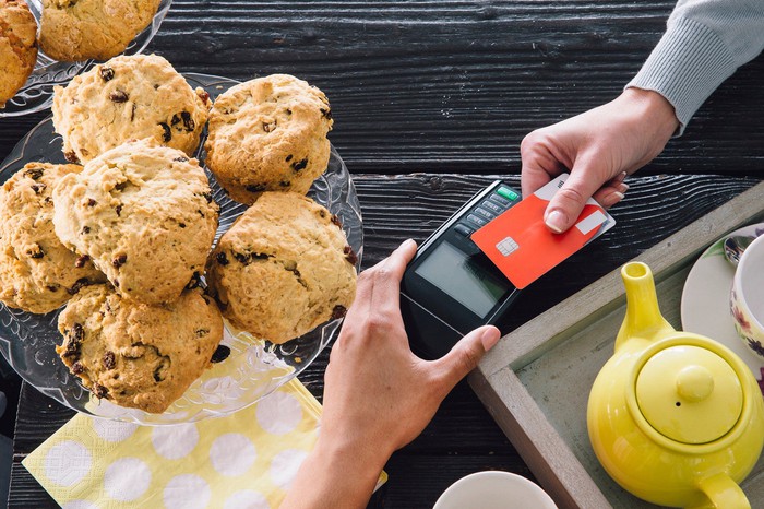 Une personne utilise une carte de crédit pour passer à la caisse d'une boulangerie. 