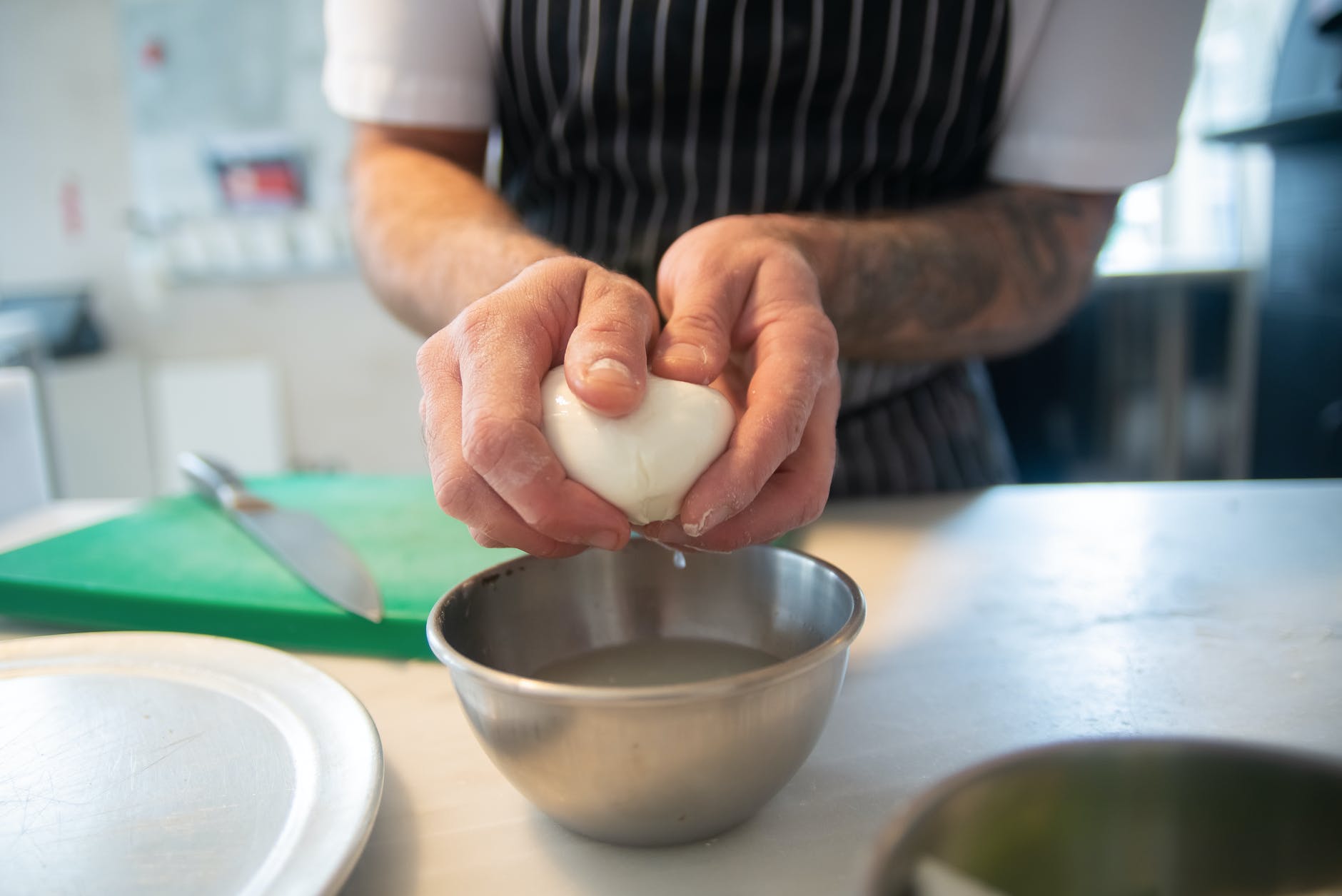 homme tenant de la mozzarella au-dessus d'un bol métallique